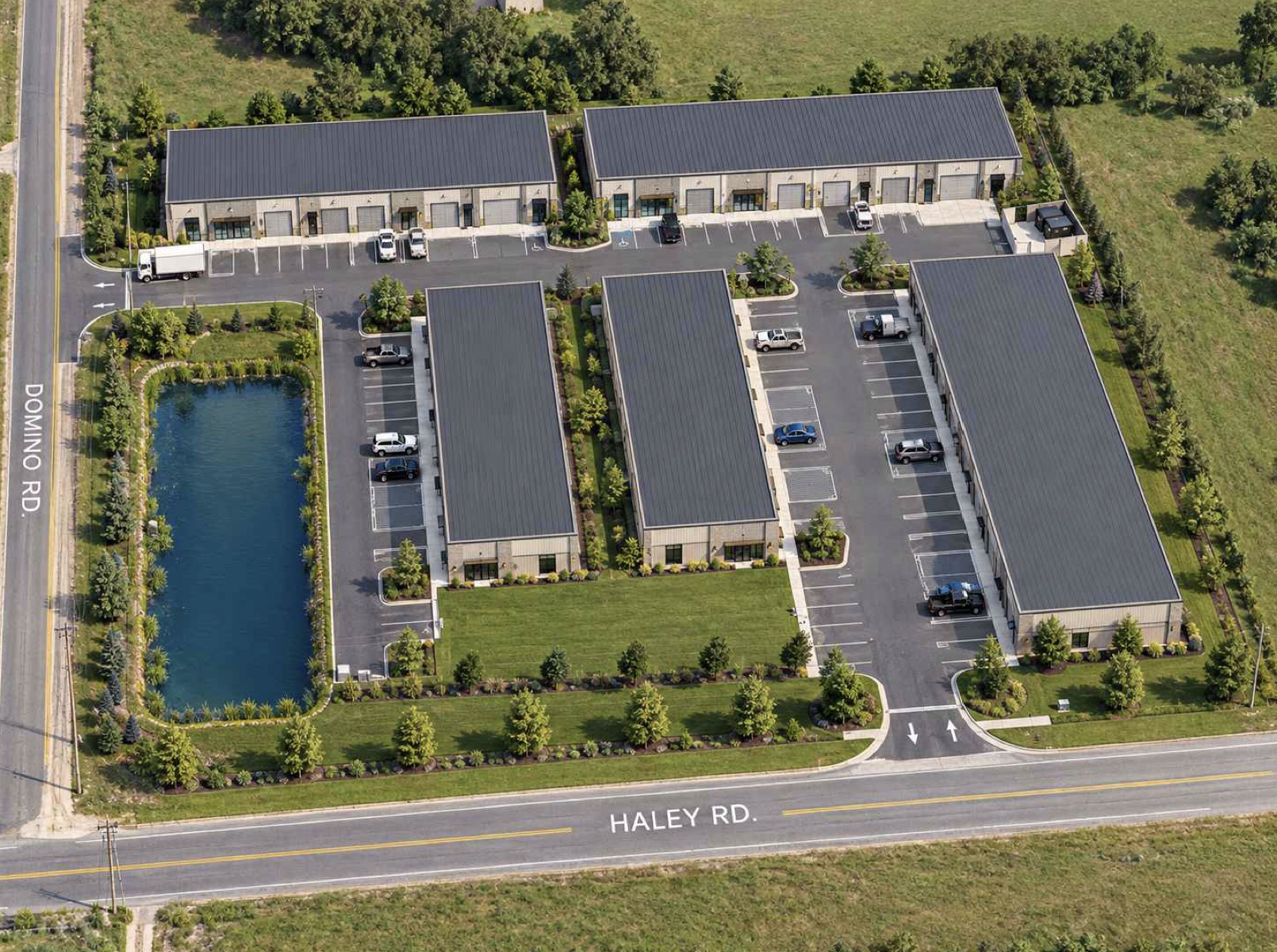 Conceptual aerial rendering: five metal flex buildings around two drives, a stormwater pond at the Domino Rd corner and an entrance on Haley Rd